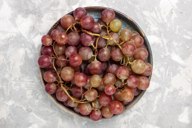 Vista superior de uvas rojas frescas jugosas frutas dulces suaves en el escritorio blanco