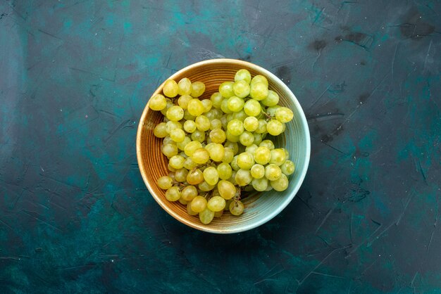 Vista superior de uvas verdes frescas dentro de la placa marrón en la fruta de uva fresca y oscura