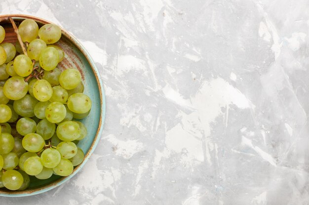 Vista superior de uvas verdes frescas jugosas frutas dulces suaves en el escritorio blanco