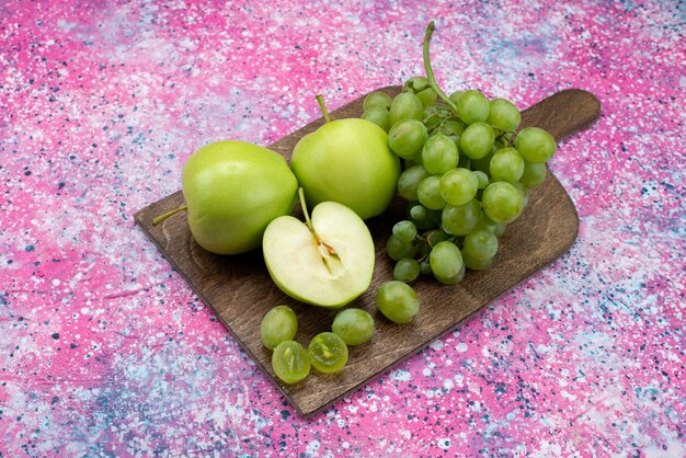 Vista superior de uvas verdes junto con manzanas verdes en el color púrpura de la fruta del escritorio.