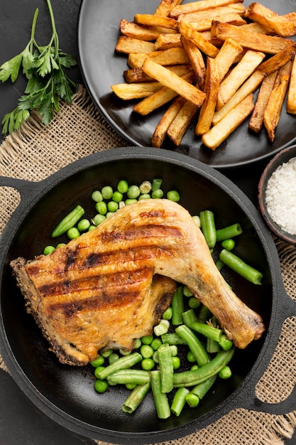 Vista superior de vainas de pollo y guisantes al horno en sartén con patatas