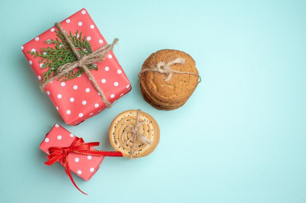 Vista superior de varias cajas de regalo rojas deliciosas galletas apiladas sobre fondo verde pastel