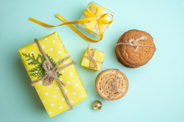 Vista superior de varias deliciosas galletas apiladas cajas de regalo amarillas sobre fondo verde pastel