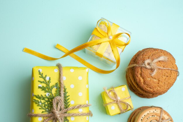 Vista superior de varias deliciosas galletas apiladas y hermosas cajas de regalo amarillas sobre fondo verde pastel
