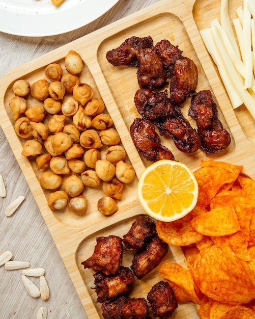 Foto gratuita vista superior de una variedad de aperitivos de cerveza como dushbara frito pollo a la parrilla y papas fritas en una tabla de madera