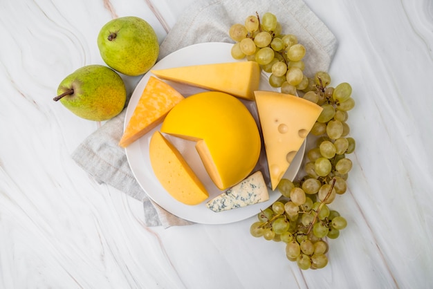 Vista superior variedad de sabroso queso con uvas y peras