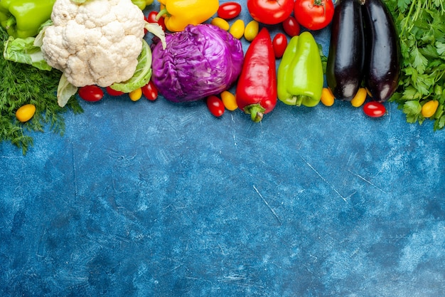 Foto gratuita vista superior de varios vegetales tomates cherry diferentes colores pimientos tomates cumcuat berenjenas coliflores repollo rojo en la parte superior del lugar de copia de mesa azul