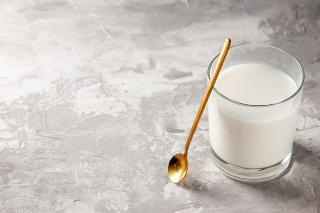 Vista superior del vaso lleno de leche y cuchara dorada en mesa gris con espacio libre