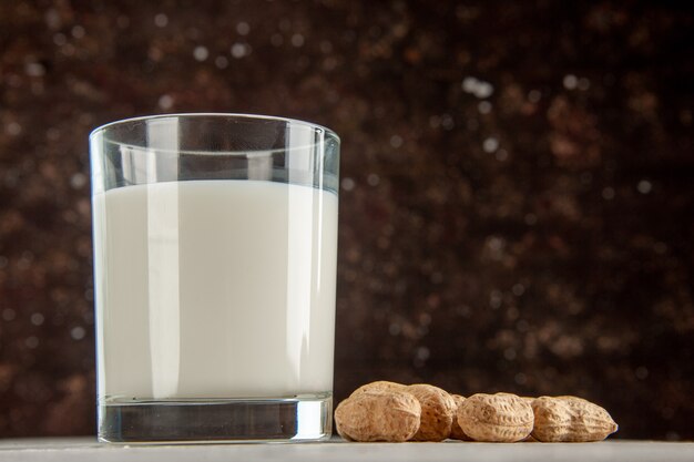 Vista superior del vaso lleno de leche y frutos secos sobre fondo oscuro