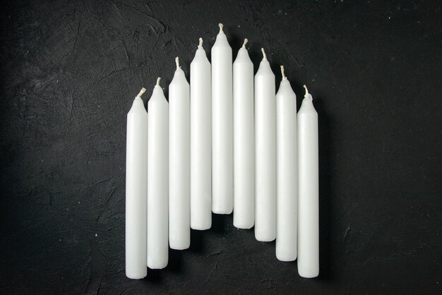 Vista superior de velas blancas en la pared oscura