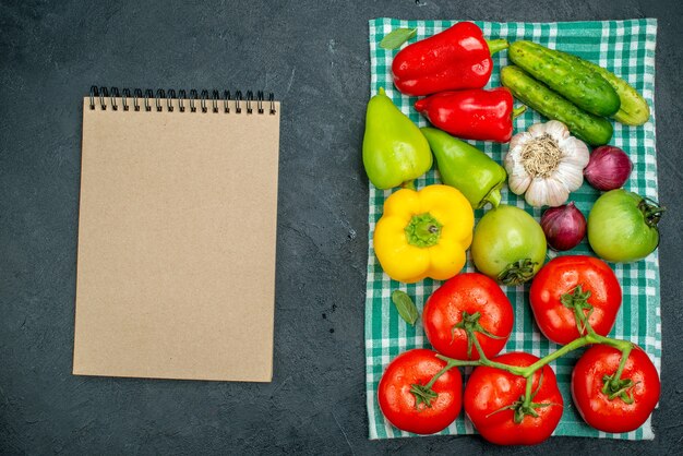 Vista superior verduras ajo pepinos cebolla roja tomate rama pimientos sobre mantel verde