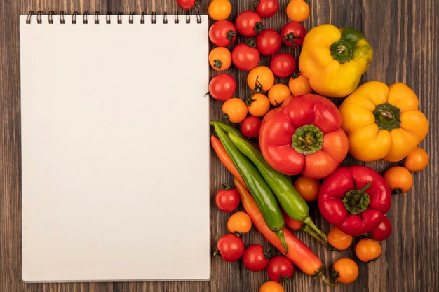 Vista superior de verduras aromatizadas como tomates cherry y pimientos aislados en una superficie de madera con espacio de copia