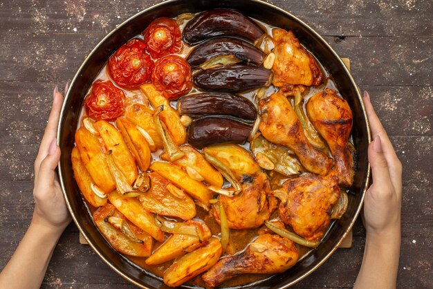 Vista superior verduras cocidas como papas tomates y berenjenas dentro de la sartén en marrón