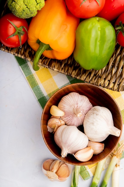 Vista superior de verduras como ajo, pimientos y tomates en cesta de mimbre