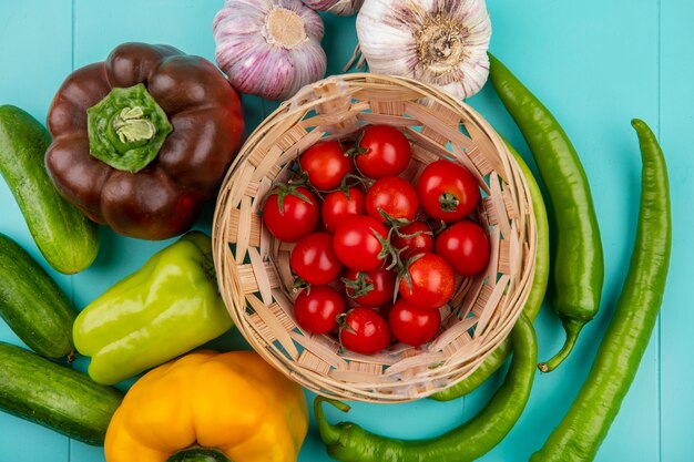 Vista superior de verduras como canasta de tomate y pepino ajo ajo sobre superficie azul