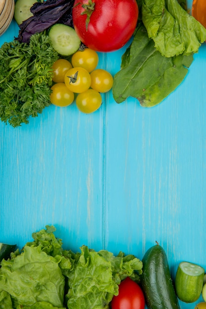 Foto gratuita vista superior de verduras como cilantro albahaca tomate espinaca lechuga pepino sobre superficie azul con espacio de copia