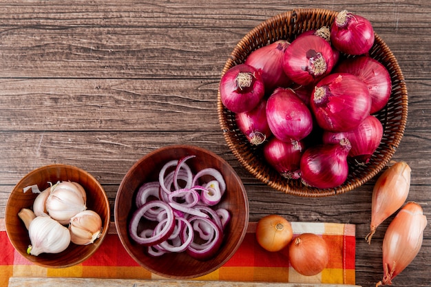 Vista superior de verduras como diferentes tipos de cebolla y ajo sobre fondo de madera con espacio de copia