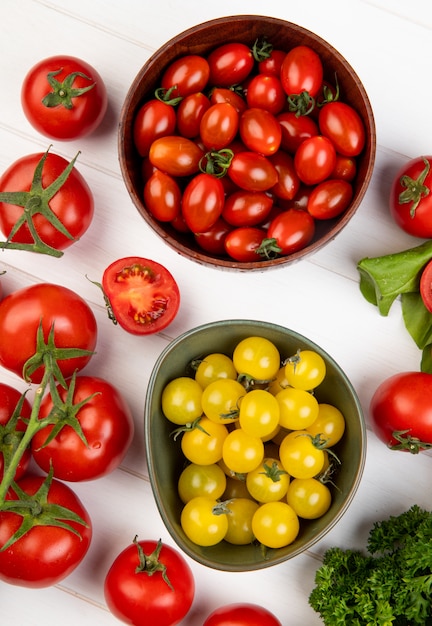 Vista superior de verduras como espinacas de tomate cilantro con cuencos de tomates en superficie de madera