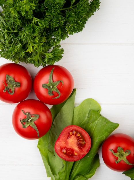 Vista superior de verduras como espinacas de tomate y cilantro en superficie de madera