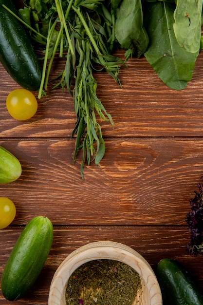 Vista superior de verduras como pepino tomate menta espinacas con pimienta negra sobre superficie de madera