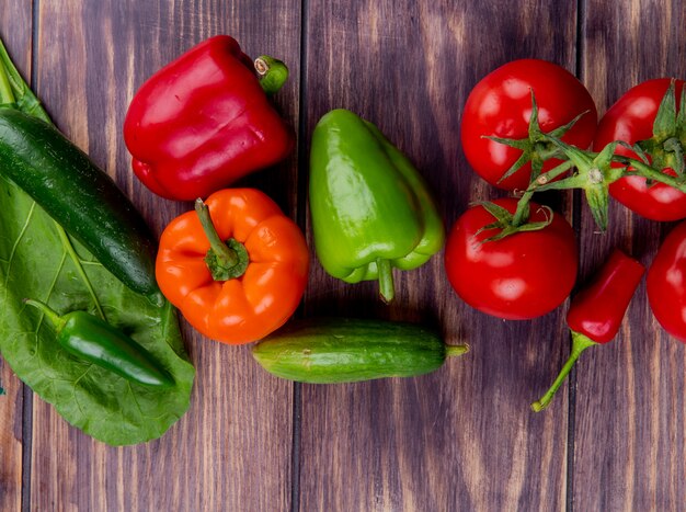 Vista superior de verduras como pepino tomate pimiento sobre superficie de madera decorada con licencia