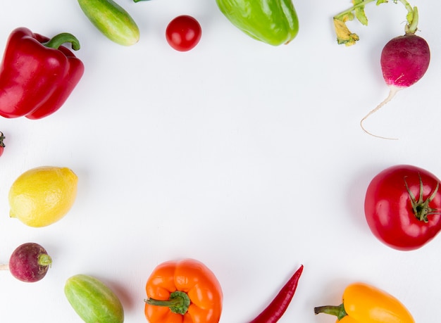 Vista superior de verduras como pimiento pepino rábano tomate en forma redonda sobre superficie blanca con espacio de copia