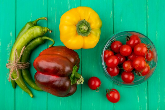 Vista superior de verduras como tazón de tomate y pimientos en superficie verde