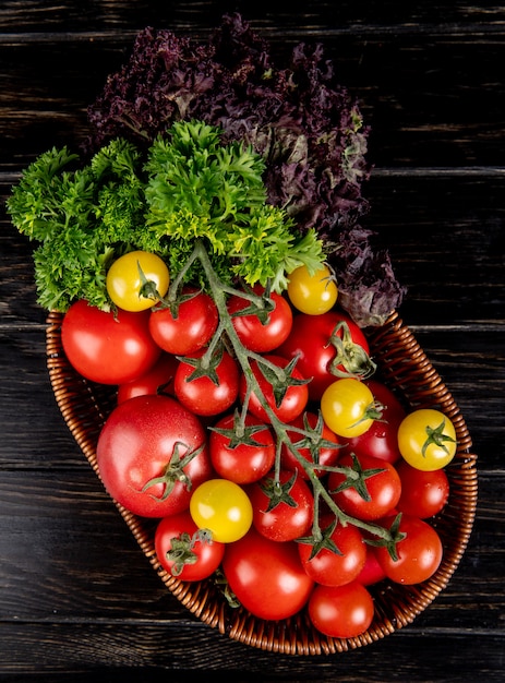 Foto gratuita vista superior de verduras como tomate cilantro albahaca en cesta sobre superficie de madera