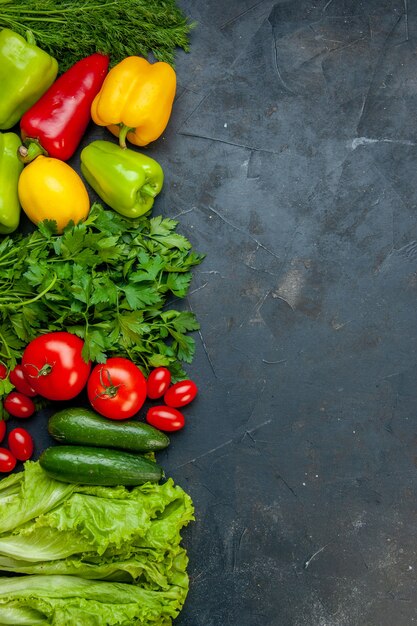 Foto gratuita vista superior de verduras de diferentes colores pimientos limón perejil tomates pepinos lechuga tomates cherry eneldo en mesa oscura con espacio de copia