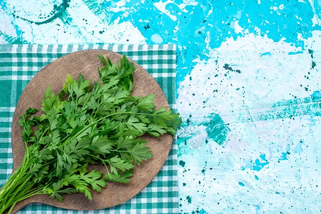 Vista superior de verduras frescas aisladas en un escritorio de madera marrón y comida de productos de hojas verdes de color azul brillante