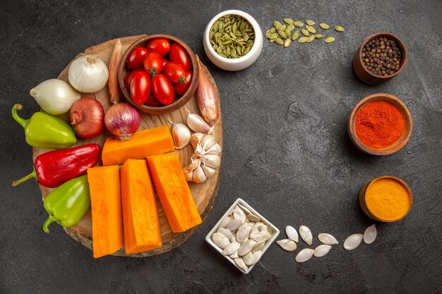 Vista superior de verduras frescas con calabaza y condimentos en el color de comida madura de ensalada de fondo oscuro