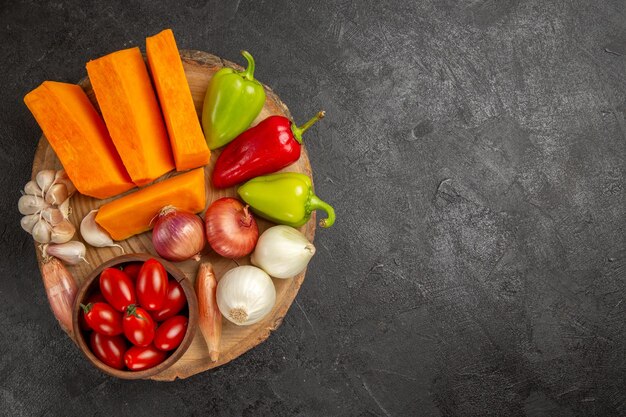 Vista superior de verduras frescas con calabaza en rodajas sobre el fondo gris oscuro color maduro fresco