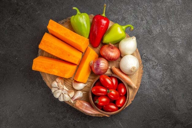 Vista superior de verduras frescas con calabaza en rodajas sobre el fondo gris oscuro color maduro fresco