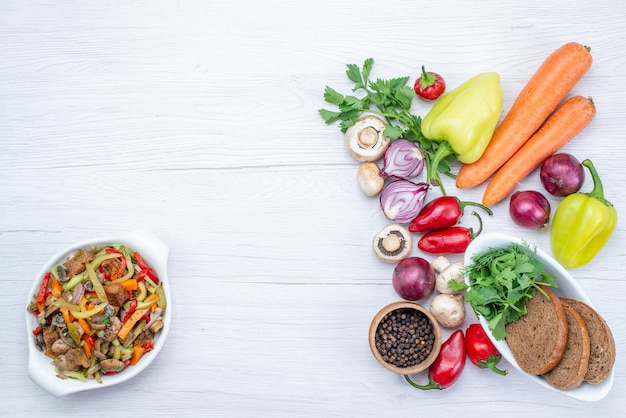 Vista superior de verduras frescas como cebollas de zanahoria pimiento con hogazas de pan en el escritorio de luz, comida vegetal vitamina