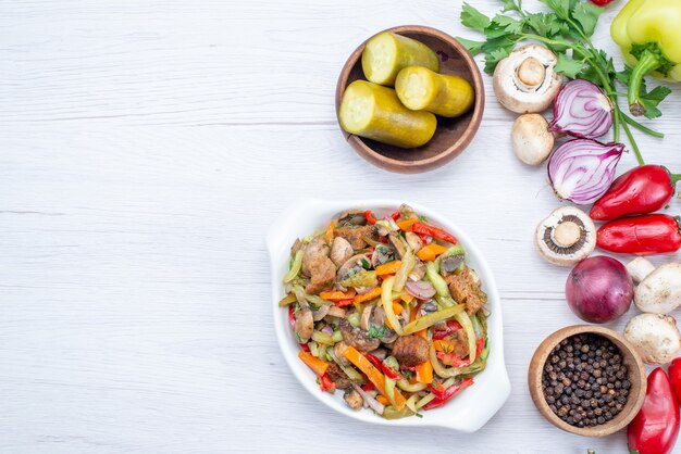 Vista superior de verduras frescas como cebollas de zanahoria pimiento con plato de carne en rodajas en un escritorio ligero, comida vegetal vitamina