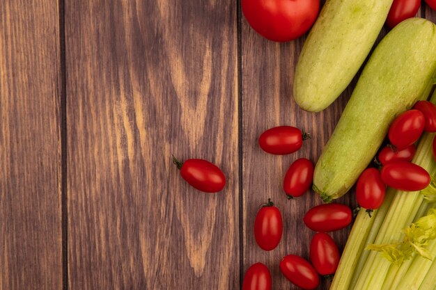 Vista superior de verduras frescas como tomates y calabacines aislados en una superficie de madera con espacio de copia