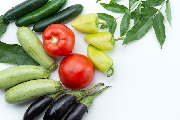 Una vista superior de verduras frescas como tomates rojos, calabazas y berenjenas en alimentos de color blanco y vegetal