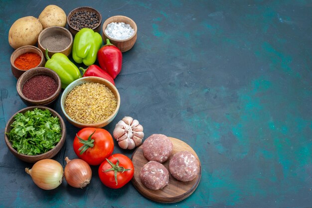 Vista superior de verduras frescas con condimentos, carne y verduras en el escritorio azul oscuro