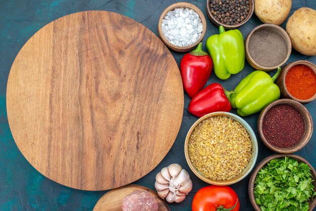 Vista superior de verduras frescas con condimentos, carne y verduras en el escritorio azul oscuro