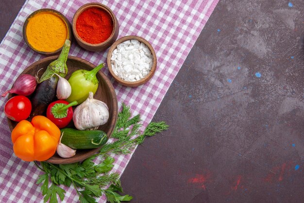 Vista superior de verduras frescas con condimentos en la superficie oscura ensalada madura comida sana