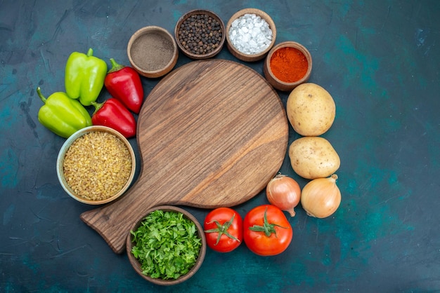 Vista superior de verduras frescas con condimentos y verduras en la superficie azul oscuro