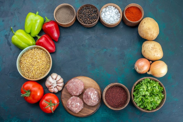 Vista superior de verduras frescas con condimentos y verduras en la superficie azul oscuro