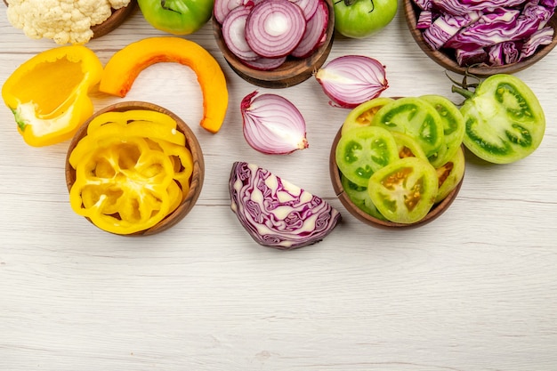 Foto gratuita vista superior verduras frescas cortadas tomates verdes cortados repollo rojo cortado cebolla cortada calabaza coliflor cortada pimiento en tazones sobre superficie blanca