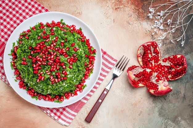 Vista superior de verduras frescas con granadas peladas en mesa de luz, fruta, comida verde, rojo