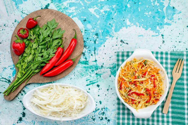 Vista superior de verduras frescas junto con ensalada de pimientos rojos picantes y repollo en azul brillante, comida vegetal verde