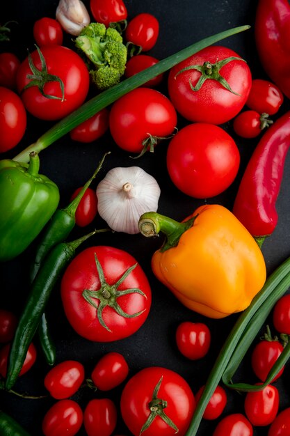 Vista superior de verduras frescas maduras coloridos pimientos tomates ajo brócoli y cebolla verde sobre fondo negro