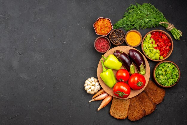 Vista superior de verduras frescas maduras con verduras y panes de pan oscuro en la superficie oscura ensalada comida comida saludable vegetal