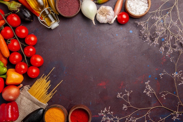 Vista superior de verduras frescas con pasta cruda italiana y condimentos en el espacio oscuro