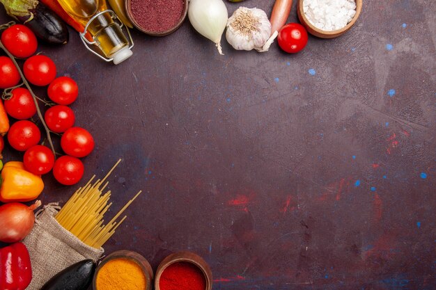 Vista superior de verduras frescas con pasta cruda italiana y condimentos en el espacio oscuro