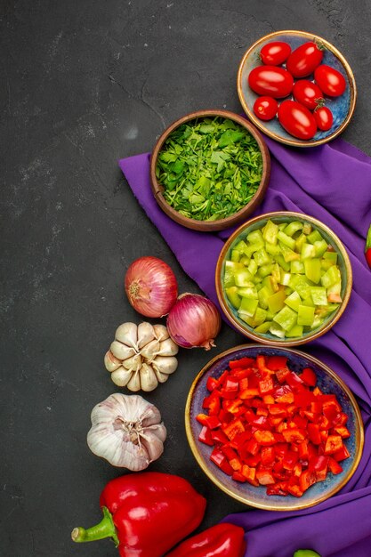 Vista superior de verduras frescas con pimienta y ajo en ensalada de mesa oscura color de comida madura